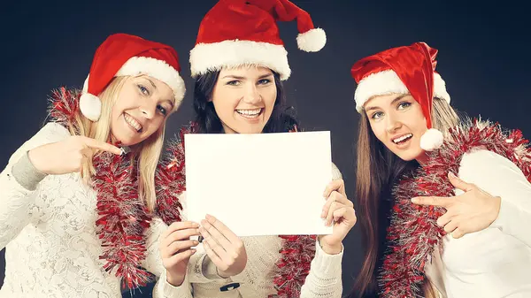 Três meninas no traje de Papai Noel mostrando folhas em branco — Fotografia de Stock
