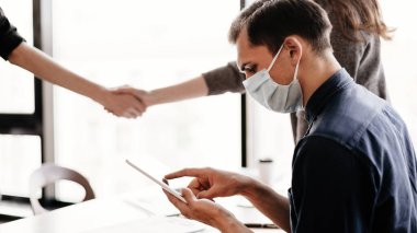 Ofis masasında dijital tabletli bir iş adamı oturuyor.