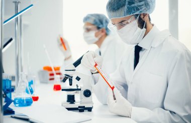 Kapat. Bilim adamı yeni bir test numunesi içeren bir tüp tutuyor..