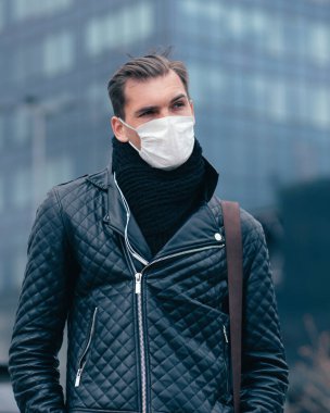 Sokakta duran koruyucu maskeli genç adam.