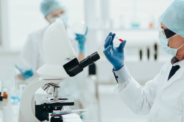 Laboratuvar masasında oturan yeni bir aşı ampulü olan bir bilim adamı.