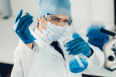 Kapat. Bilim adamı tıbbi şişedeki sıvıyı inceliyor..