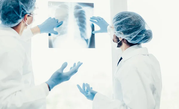 Kapat. Koruyucu maskeli bilim adamları akciğerlerin röntgenine bakıyor. . — Stok fotoğraf