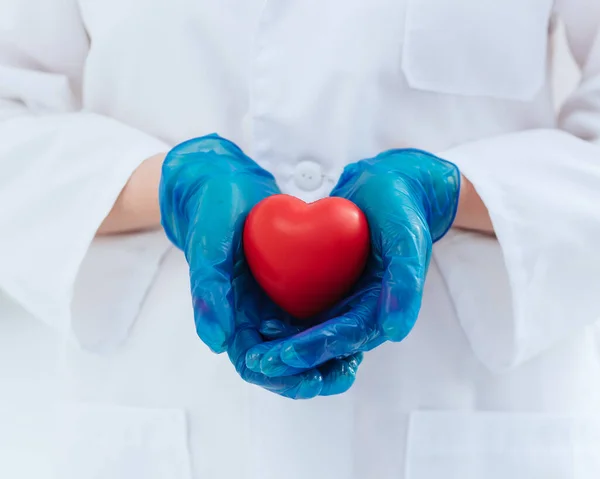 Doe dicht. arts in beschermende handschoenen houdt het hart vast . — Stockfoto