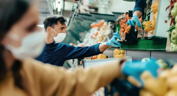 Acheteurs en masques protecteurs choisissant des fruits au supermarché — Photo