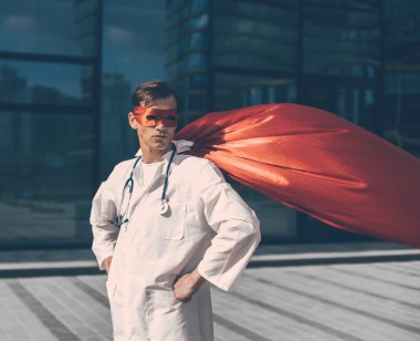 Şehrin caddesinde duran süper kahraman pelerinli ciddi bir doktor.