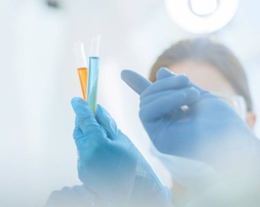 Kapat. Kadın bir bilim adamının ellerinde testler olan bir tüp görüntüsü..