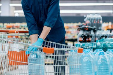 Alışveriş katındaki alışveriş arabalı koruyucu maskeli adam.