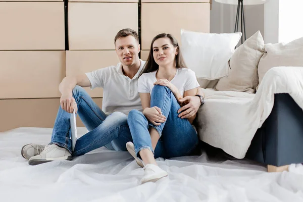 Feliz pareja sentada en el suelo en un nuevo apartamento — Foto de Stock