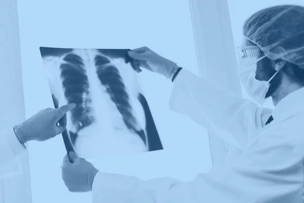 Kapat. Koruyucu maskeli doktorlar akciğerlerin röntgenini tartışıyor. . — Stok fotoğraf