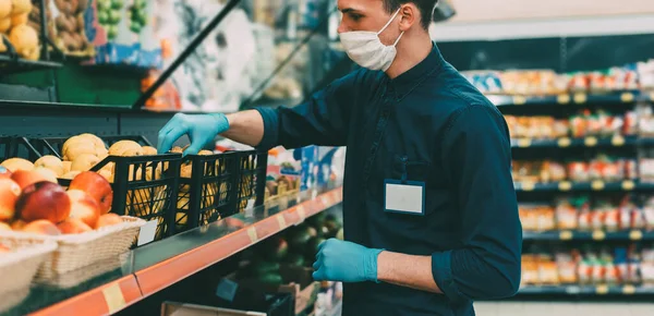 Seller in a protective mask standing in front of the counter with fruit. — Stock Photo, Image