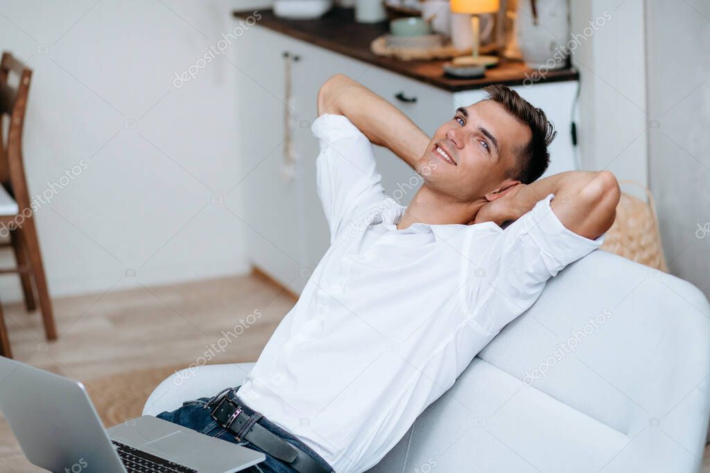 dreaming young man with a laptop sitting on the couch.