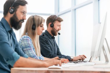 Kapat. Çağrı merkezi operatörleri modern bir ofiste çalışır..