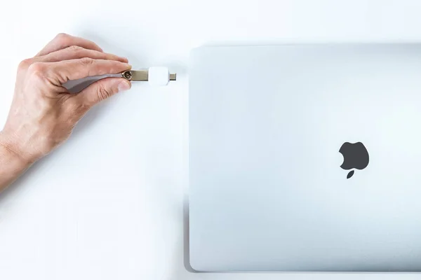 Bělorusko, Minsk - 13. července 2020: Apple Inc. produktový design Space gray Macbook Pro. muž vkládá flash kartu do MacBooku Pro. — Stock fotografie