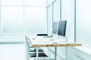 Boş bir ofiste dizüstü bilgisayarı ve bilgisayarı olan bir masaüstü.