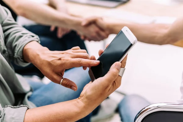 Fecha. uma mulher de negócios usa um smartphone durante uma reunião de trabalho. — Fotografia de Stock