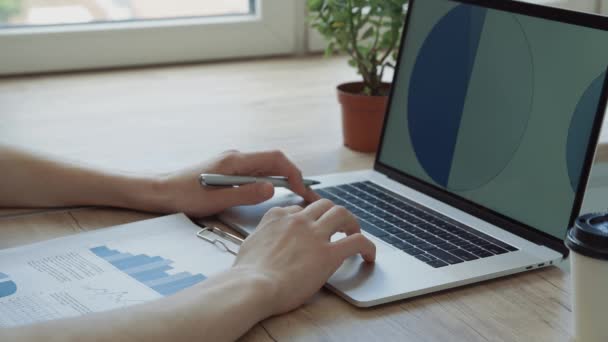 Jonge ondernemer met behulp van zijn laptop om te werken met financiële gegevens. — Stockvideo