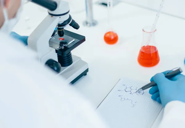 Fecha. cientista olhando para uma gota de sangue através de um microscópio. — Fotografia de Stock
