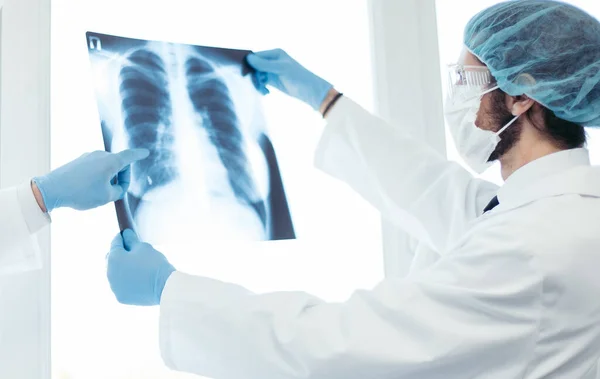 Kapat. Koruyucu maskeli doktorlar akciğerlerin röntgenini tartışıyor. . — Stok fotoğraf