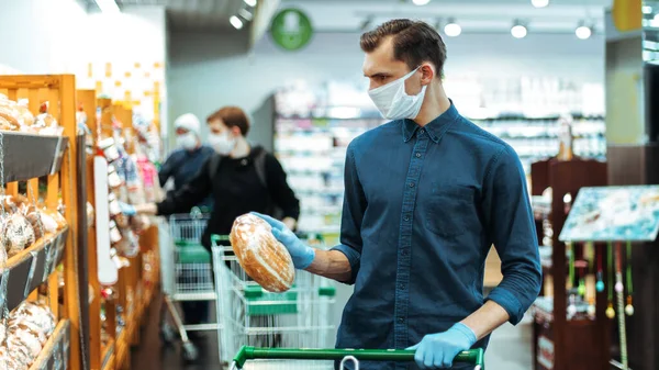 De près. jeune homme achetant du pain dans un supermarché. — Photo