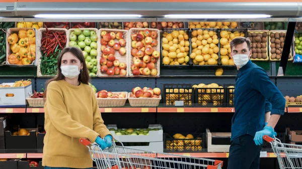 Homme et femme avec chariots dans un supermarché pendant la période de quarantaine. — Photo