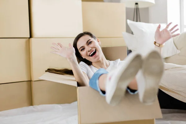 Веселая молодая женщина сидит в картонной коробке — стоковое фото