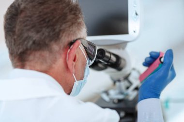 Kapat. Laboratuarda mikroskop kullanan bir bilim adamı..