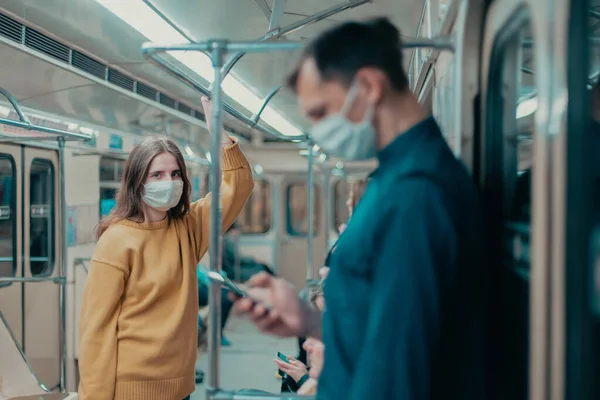 Jovem mulher em uma máscara protetora de pé em um carro de metrô. — Fotografia de Stock