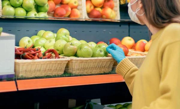 Femme décontractée en masque de protection et gants acheter des fruits. — Photo