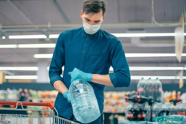 Homme dans un masque de protection achetant de l'eau dans un supermarché — Photo