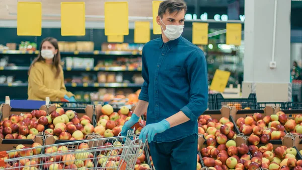 Shoppers in protective masks standing in a supermarket at a safe distance — Stock Photo, Image