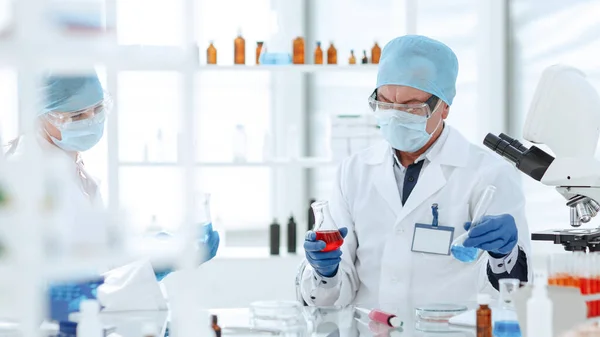 Colegas cientistas verificando o líquido em frascos de laboratório. — Fotografia de Stock