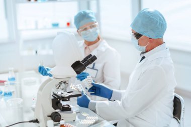 Laboratuvar masasında oturan yeni ilaç örnekleriyle bilim adamları.