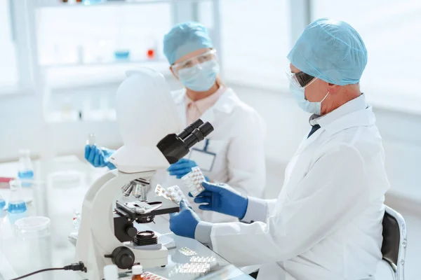 Científicos con muestras de nuevos fármacos sentados en una mesa de laboratorio. —  Fotos de Stock