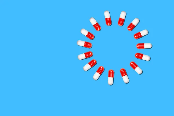 Circle of medical capsules on a blue background. — Stock Photo, Image