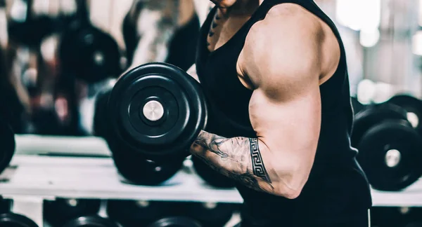 Stilig power atletisk man på motion pumpar upp muskler, hantlar. — Stockfoto