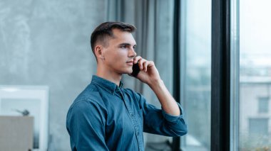 Adam not defterine not alıyor, pencerenin yanında duruyor..