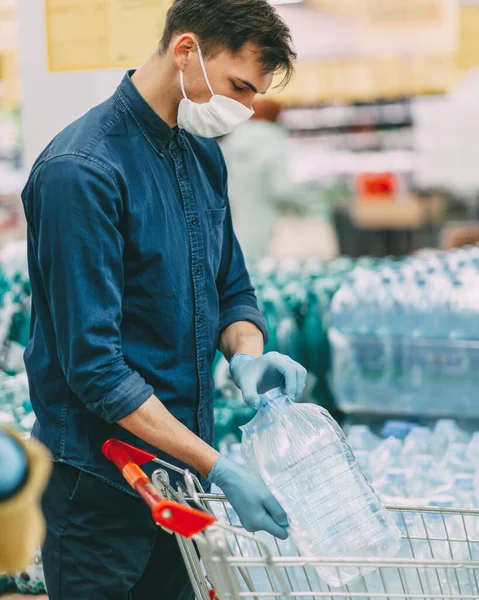 De près. homme dans un masque de protection choisissant bouteille d'eau. — Photo