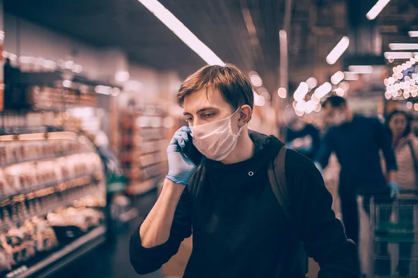 De près. jeune homme dans un masque de protection parlant sur son smartphone. — Photo