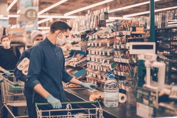 Groupe d'acheteurs dans des masques de protection debout près de la caisse dans un supermarché — Photo