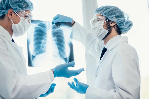 De cerca. científicos en máscaras protectoras mirando una radiografía de los pulmones . — Foto de Stock