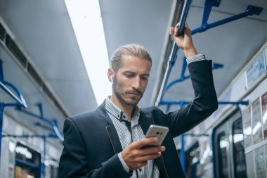 İş adamı metroda e-postalarını kontrol ediyor..