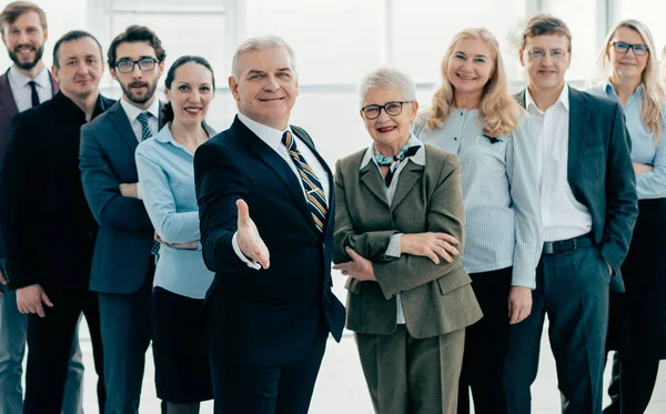 Bienvenida hombre de negocios de pie frente a un gran equipo de negocios. — Foto de Stock