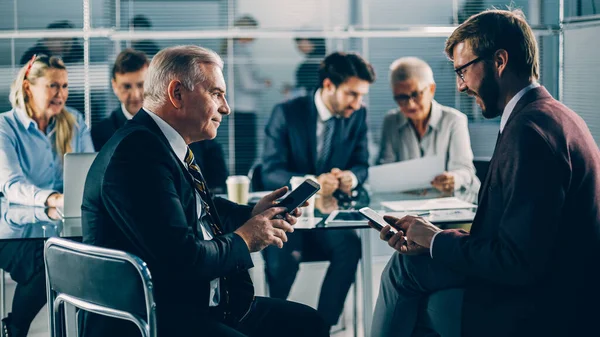 Colleghi di lavoro che utilizzano i loro smartphone durante una riunione di lavoro — Foto Stock