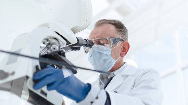 Kapat. Laboratuvar mikroskobu kullanan ciddi bir bilim adamı..