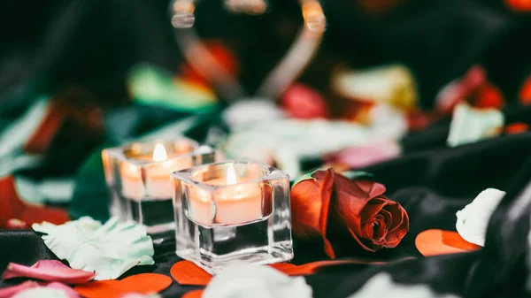 Duas velas e pétalas de flores em um fundo festivo borrado — Fotografia de Stock