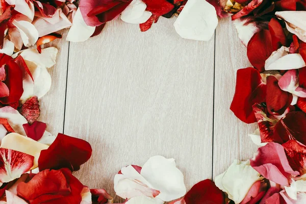 Rám okvětních lístků růží na dřevěném pozadí — Stock fotografie