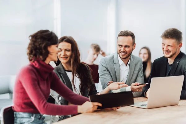 Werknemers bespreken werkdocumenten die aan een bureau zitten — Stockfoto