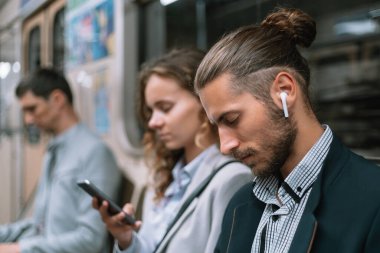 Metro vagonunda akıllı telefon kullanan yolcular. .