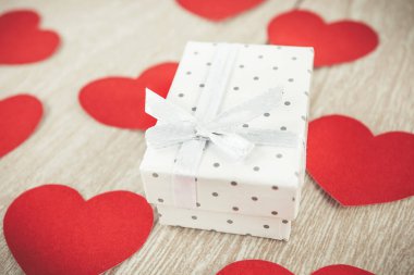 kırmızı kalpler ve hediye kutusu açık ahşap arka planda